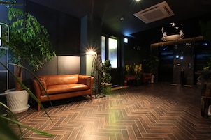 Un intérieur moderne avec un parquet en chevrons, un canapé en cuir et des plantes en pot.
