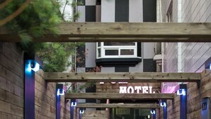 Un chemin en bois mène à l’entrée d’un hôtel, où un panneau indique « MOTEL ».