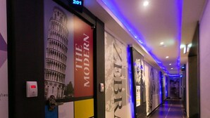 Un couloir d’hôtel au design moderne, avec un panneau distinctif représentant un zèbre et la porte numéro 201.
