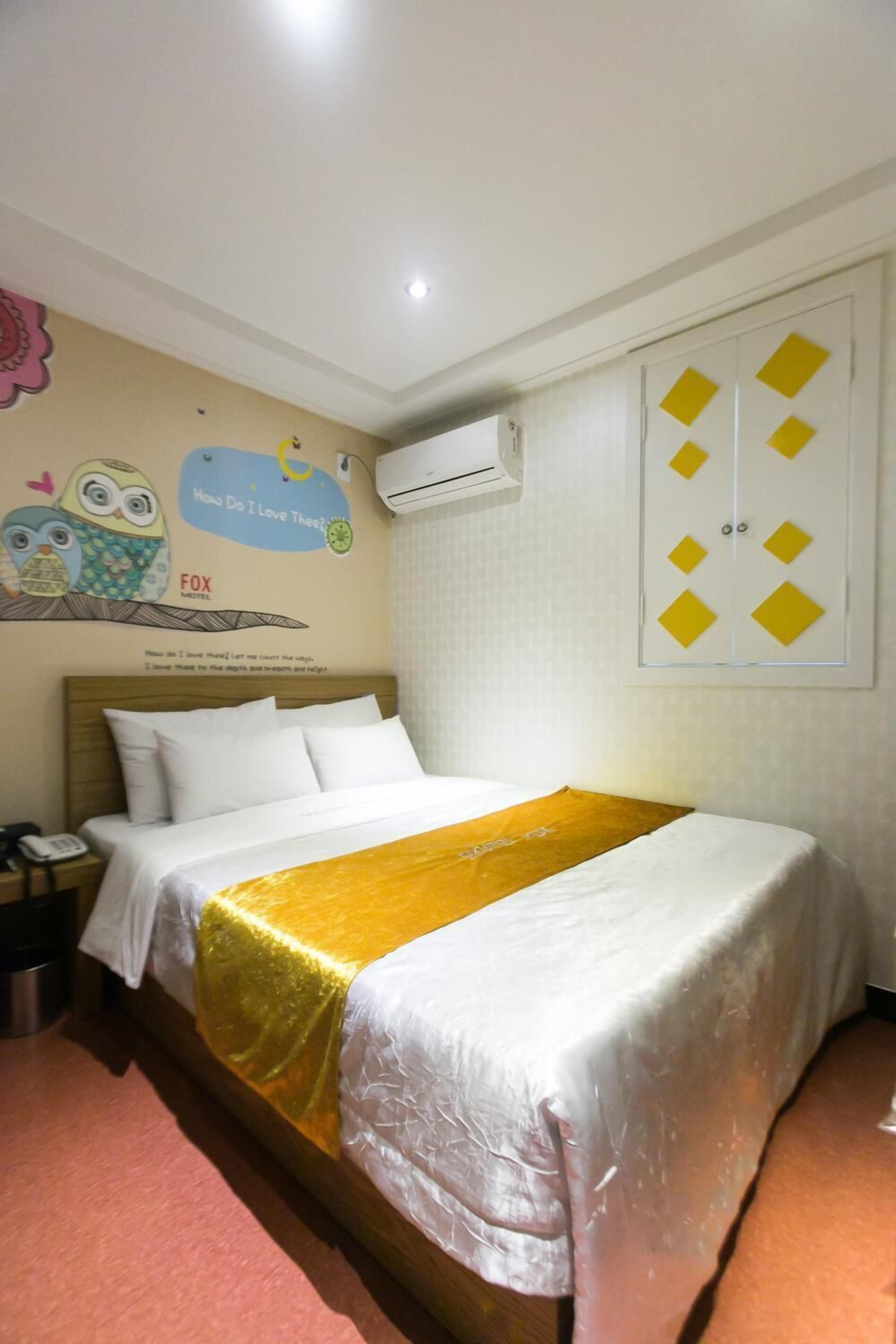 Une chambre d’hôtel comprenant un lit, une table de chevet, un élément décoratif mural et une armoire.