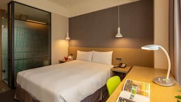 Una camera d'albergo con un letto grande, una scrivania con una lampada, una sedia e una mappa appesa al muro.