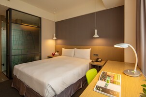 Een hotelkamer met een groot bed, een bureau met lamp, een stoel en een kaart aan de muur.