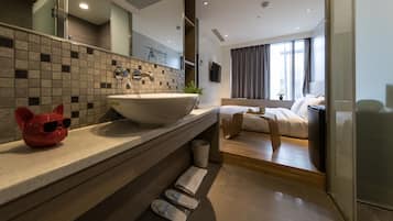 A modern bathroom with a large sink, a mirror, and a red cat-shaped soap dispenser.