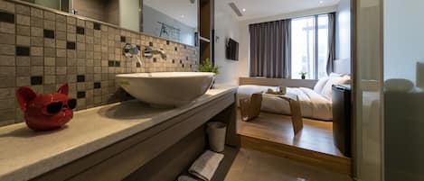 A modern bathroom with a large sink, a mirror, and a red cat-shaped soap dispenser.