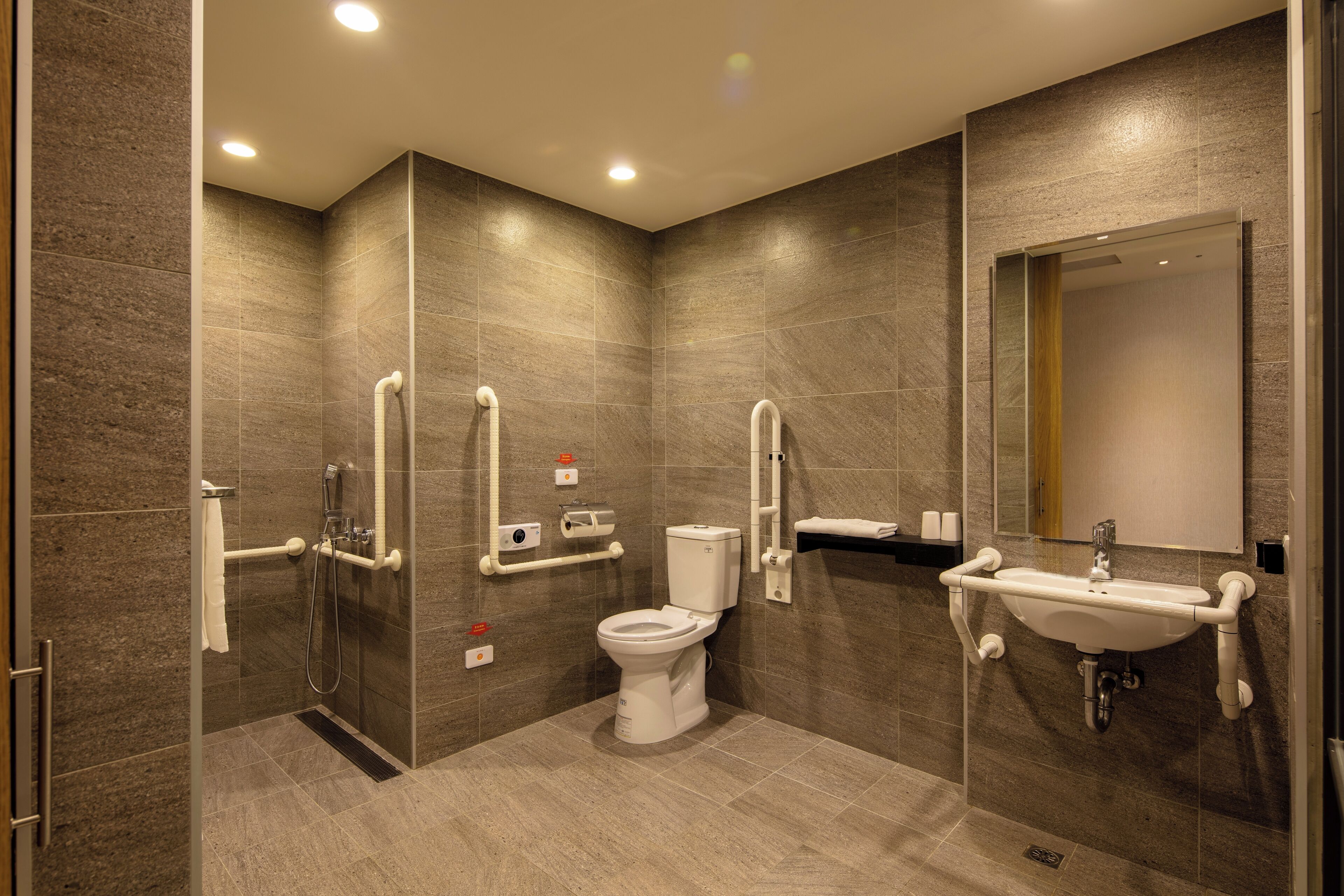 A modern bathroom with a shower, toilet, and sink, featuring a sleek design and ample lighting.
