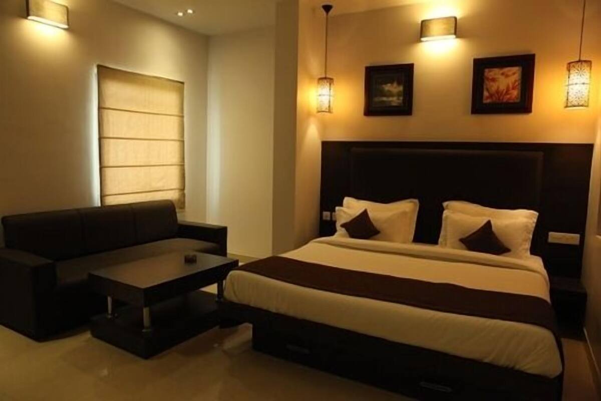 Una habitación de hotel con cama, sofá, mesa de centro e iluminación en la pared.