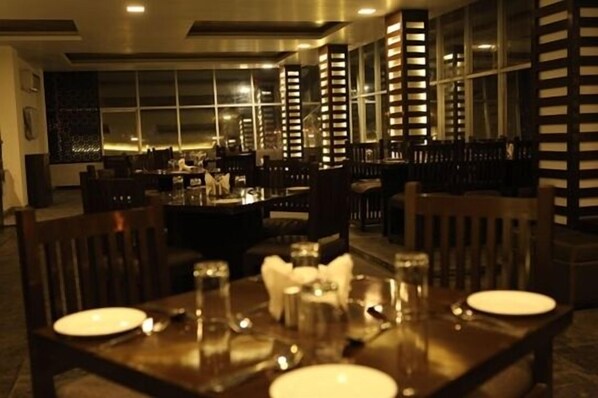 A restaurant with a dark wooden interior, large windows, and a central bar area.