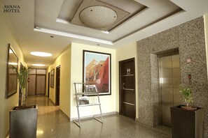 Welcome to our hotel lobby, featuring a long corridor with doors, a reception desk, and a unique light fixture.