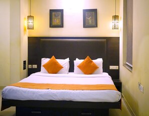 Relax in a spacious room with a large bed, flanked by wall-mounted lights and adorned with framed artworks.