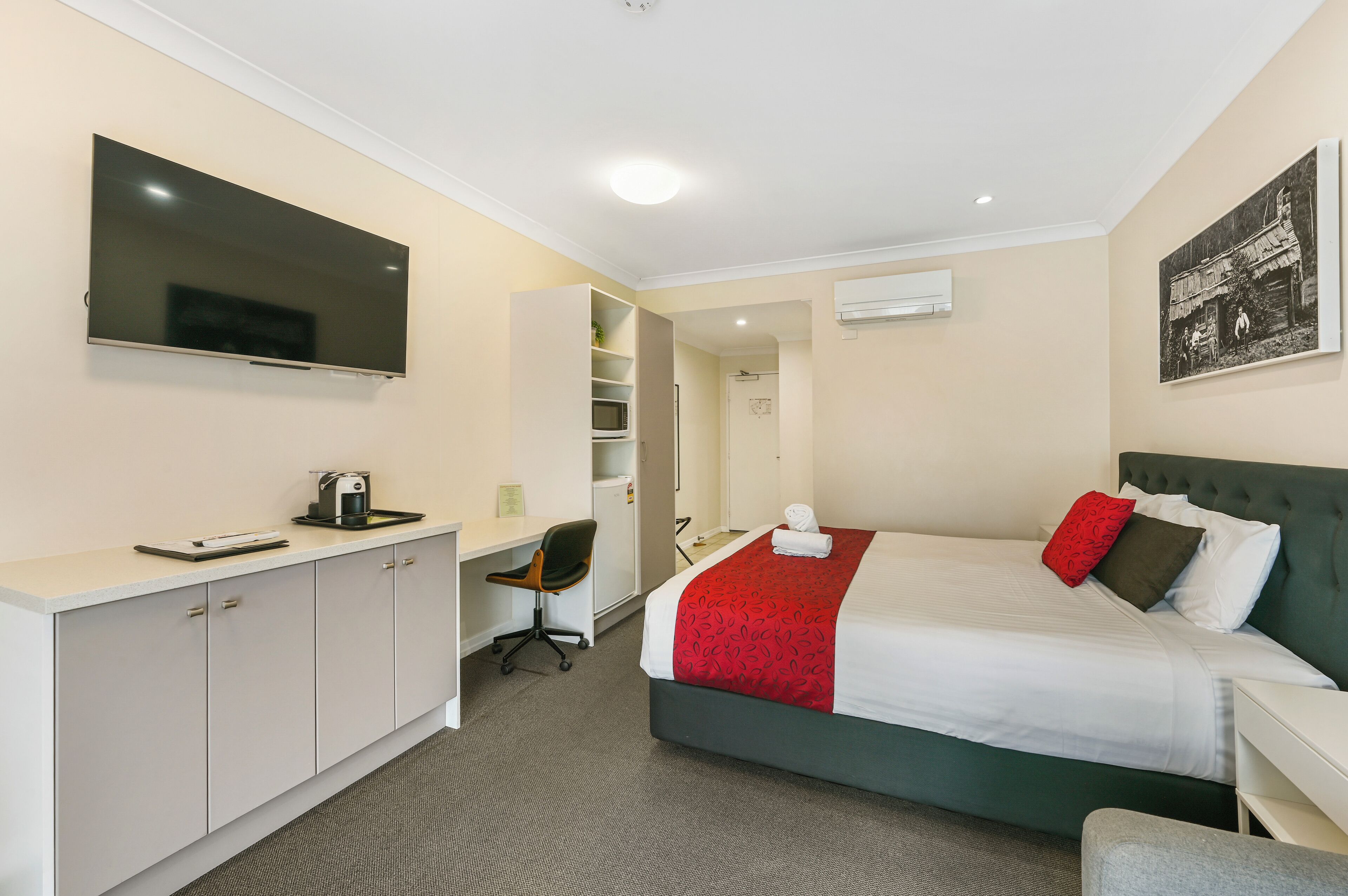 Ein Hotelzimmer mit Bett, Schreibtisch, Stuhl und Fernseher.