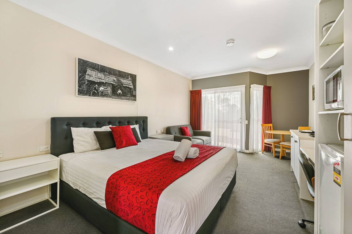 A hotel room with a bed, a desk, a chair, a television, and a window with curtains.