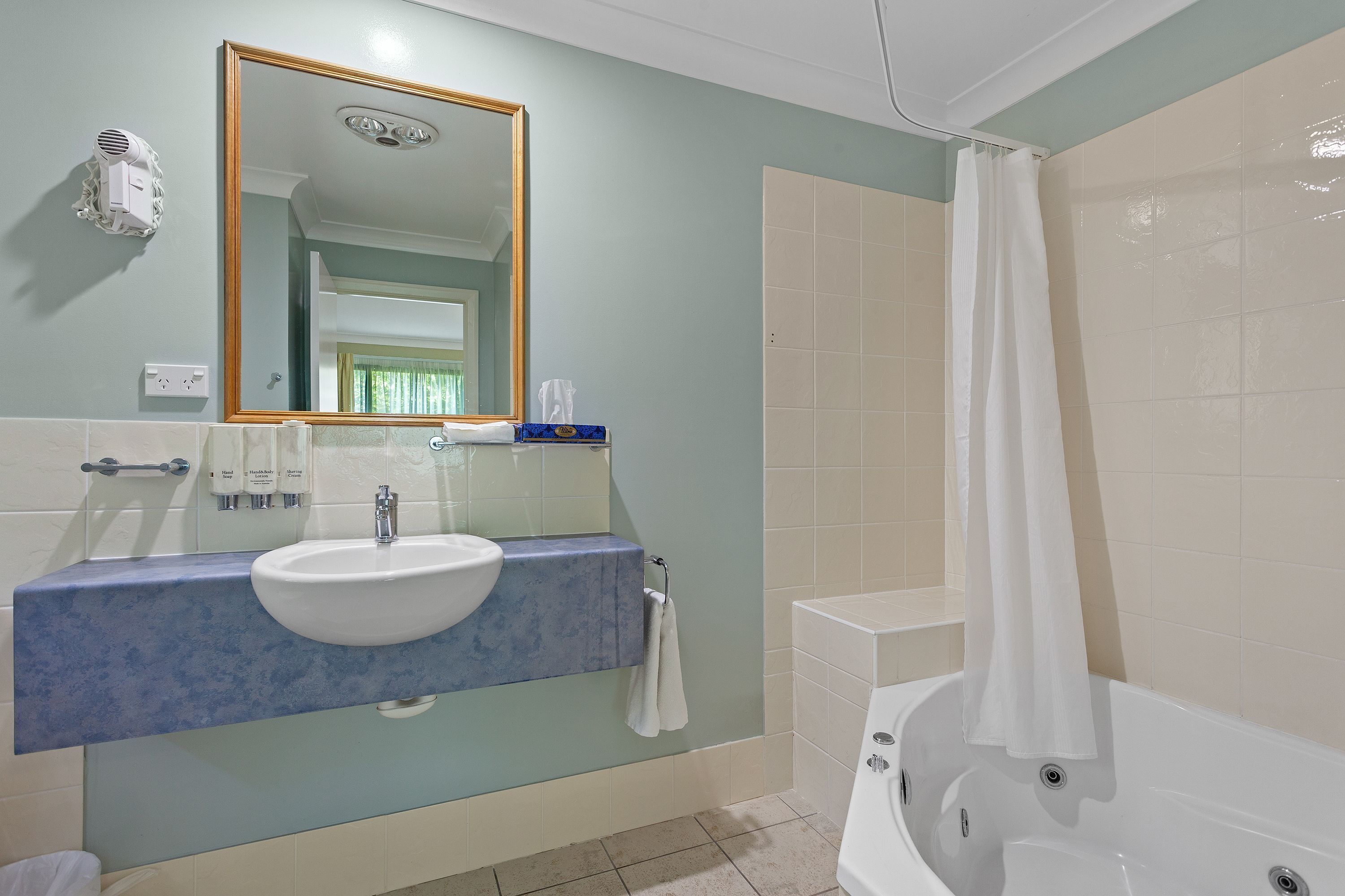 A bathroom with a sink, mirror, and bathtub.
