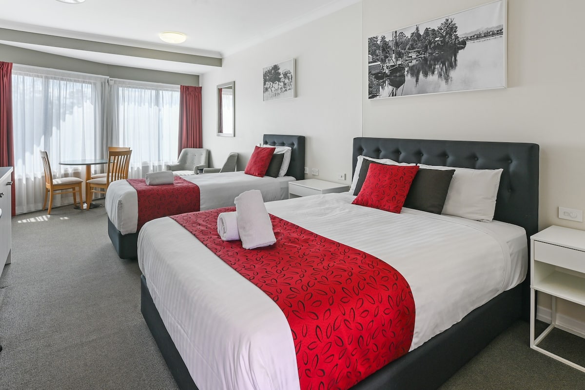 A hotel room with two beds, a desk, and a chair.
