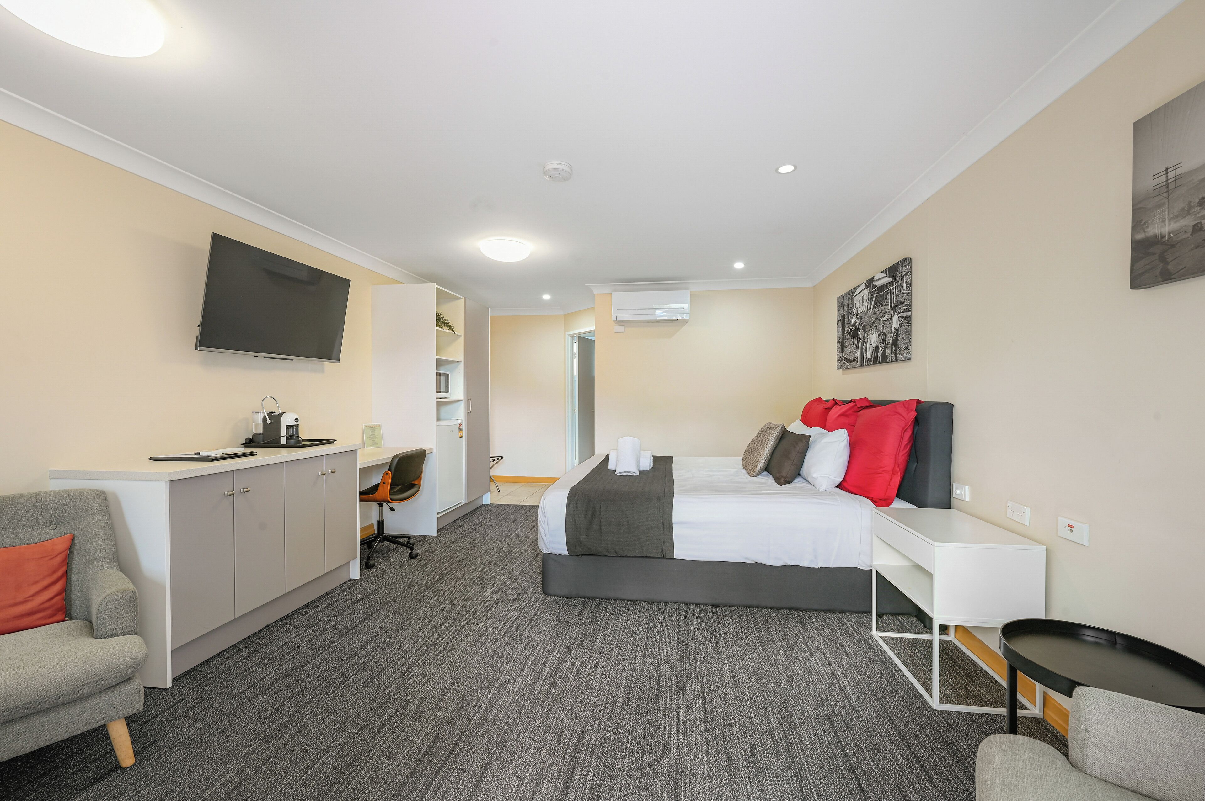 Una habitación de hotel con cama, escritorio, silla, televisor y armario.