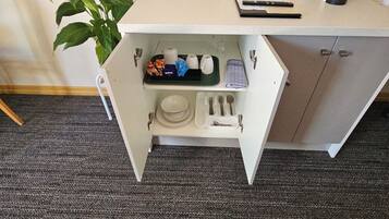 A kitchenette with a countertop, a coffee maker, and a plant.
