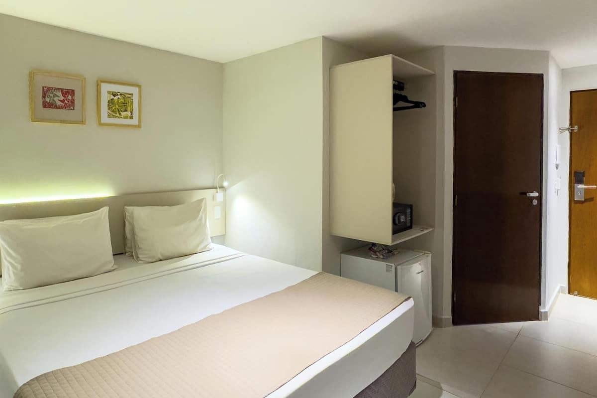 A hotel room with a bed, bedside table, and a wardrobe.