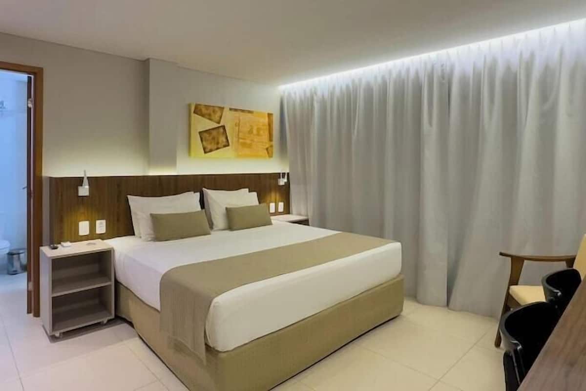 A hotel room with a bed, bedside tables, a desk, and a chair.