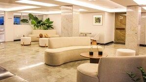 A modern lobby with a curved sofa, ottomans, a round table, and a large plant.