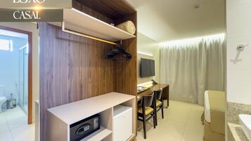 Una habitación de hotel moderna con un muro decorativo de madera, un escritorio con silla, un televisor y una zona de ducha.