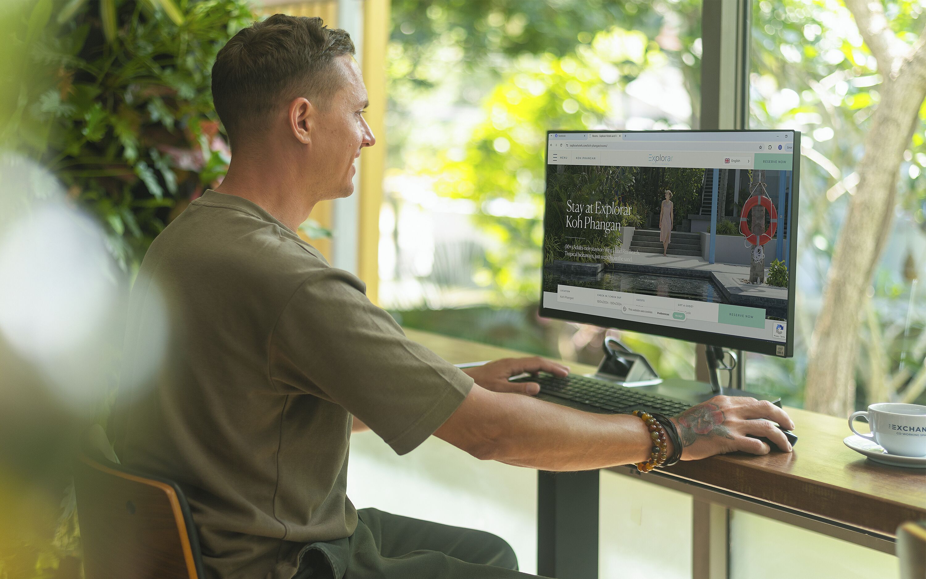 A person using a computer at a table with a view of a building outside.