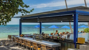 A bar with a view of the ocean, outdoor seating, and umbrellas.