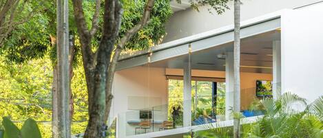 Una casa moderna con balcón de cristal que da a un jardín exuberante.