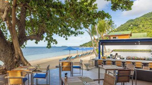 Un restaurante frente a la playa con terraza, bar y vistas al mar.