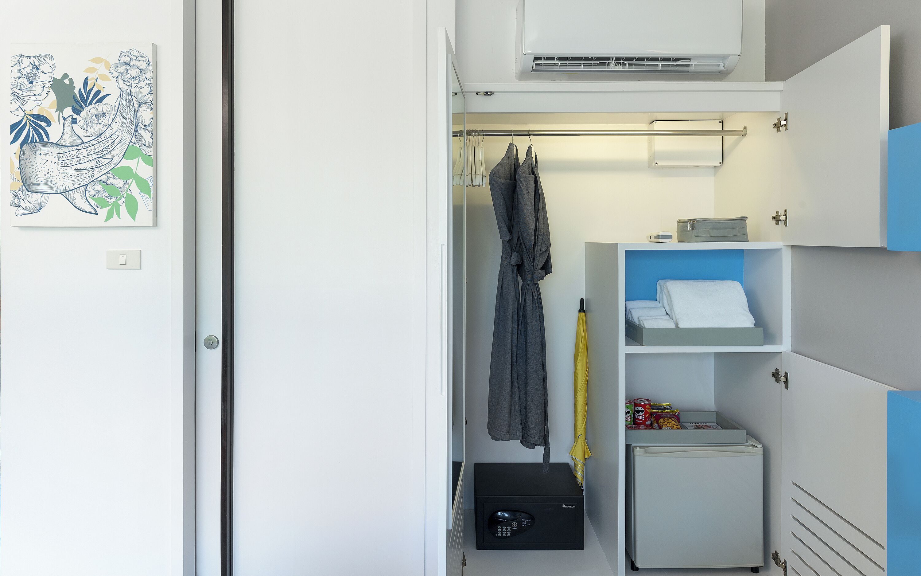 Habitación pequeña con cama, refrigerador, microondas y perchero.