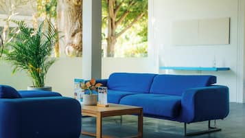 Een moderne woonkamer met een blauwe bank, een houten salontafel en een potplant.