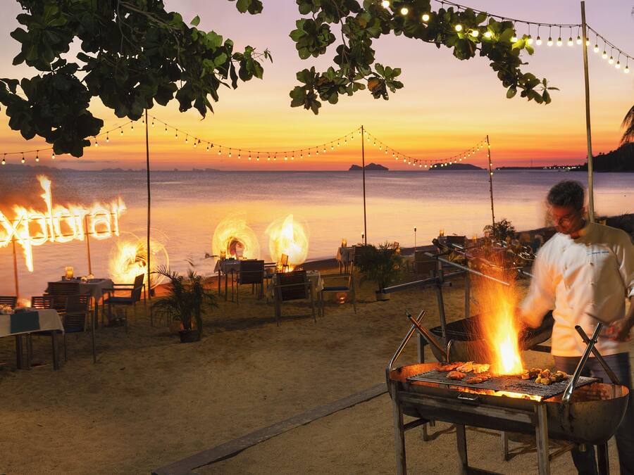 A beachside restaurant with outdoor seating and a grill.