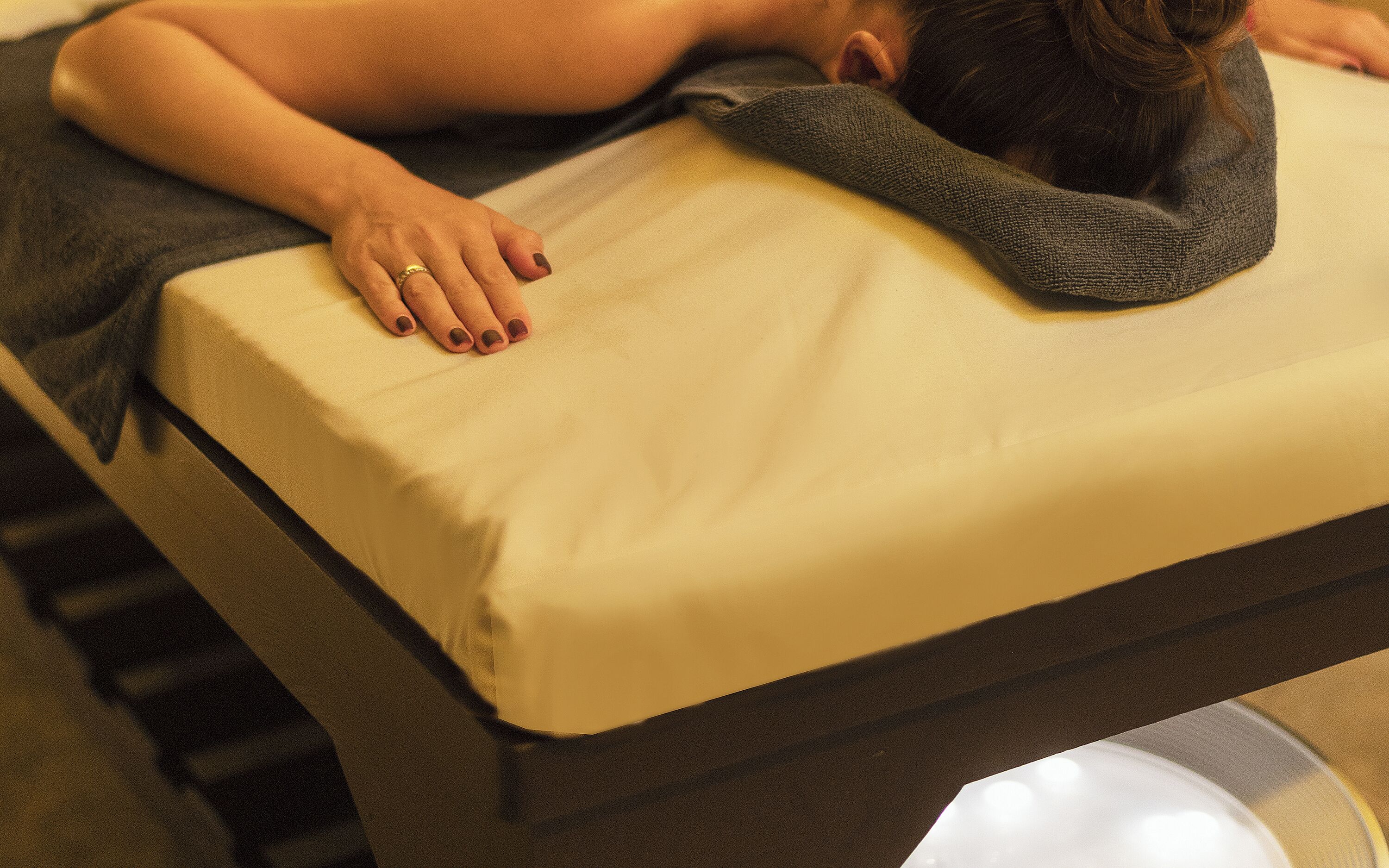 Eine Person liegt mit Kopfkissen und Decke im Bett.