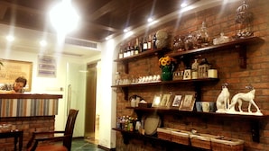 A bar area with a brick wall, shelves with bottles and glasses, and a counter with a person behind it. - Qingdao Villa Inn Seaside (Qingdao)