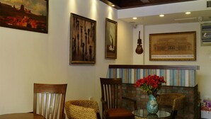 A room with a brick wall, wooden chairs, a round table, and a vase with red flowers. - Qingdao Villa Inn Seaside (Qingdao)