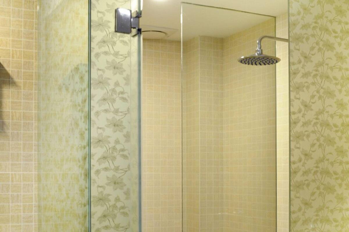 A bathroom with a glass-enclosed shower, a toilet, and a sink.
