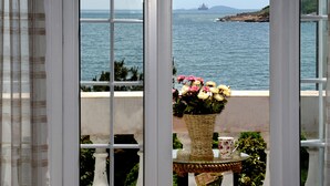 A view through a window with a wicker basket containing flowers and a teacup on a small table. - Qingdao Villa Inn Seaside (Qingdao)