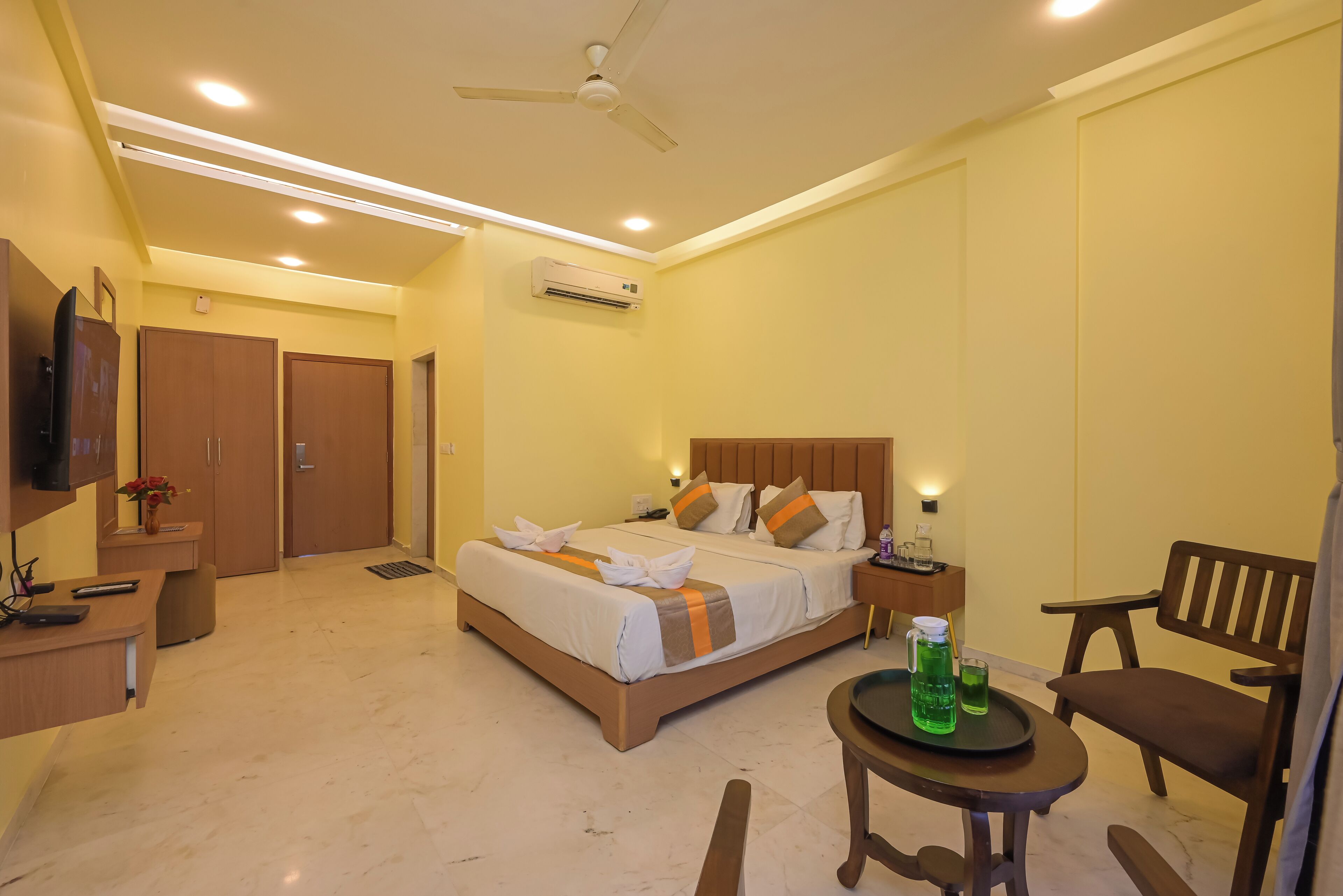 A hotel room with a bed, bedside tables, a desk, a chair, and a TV.