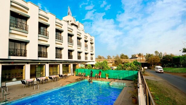 A hotel with a swimming pool, multiple balconies, and a view of the surrounding area. - Hotel Aristro (Mawal)