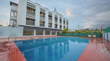 Un hotel moderno con piscina, balcones y vistas del entorno.