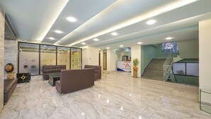 A spacious lobby with a reception desk, seating area, and a staircase. - Hotel Aristro (Mawal)