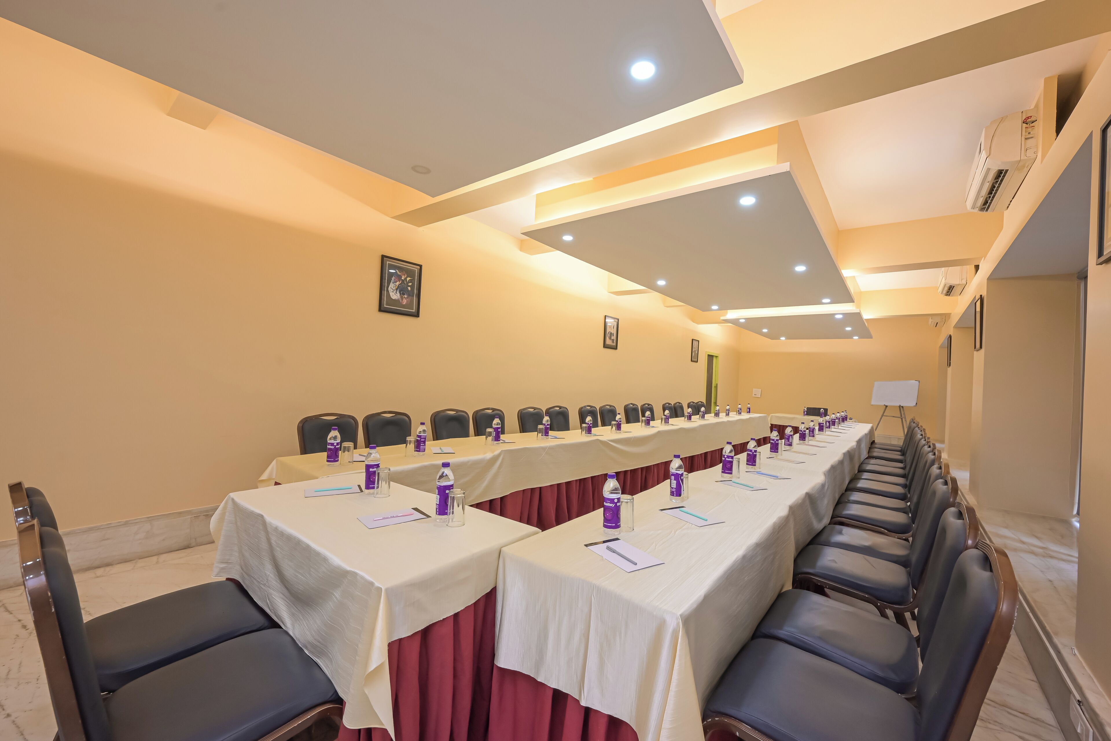 Un salón de conferencias con una mesa larga, sillas y botellas de agua.