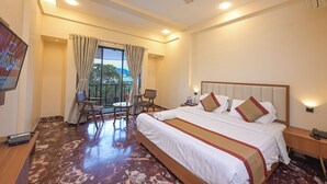 A hotel room with a large bed, a desk, a chair, and a balcony with a view. - Hotel Aristro (Mawal)