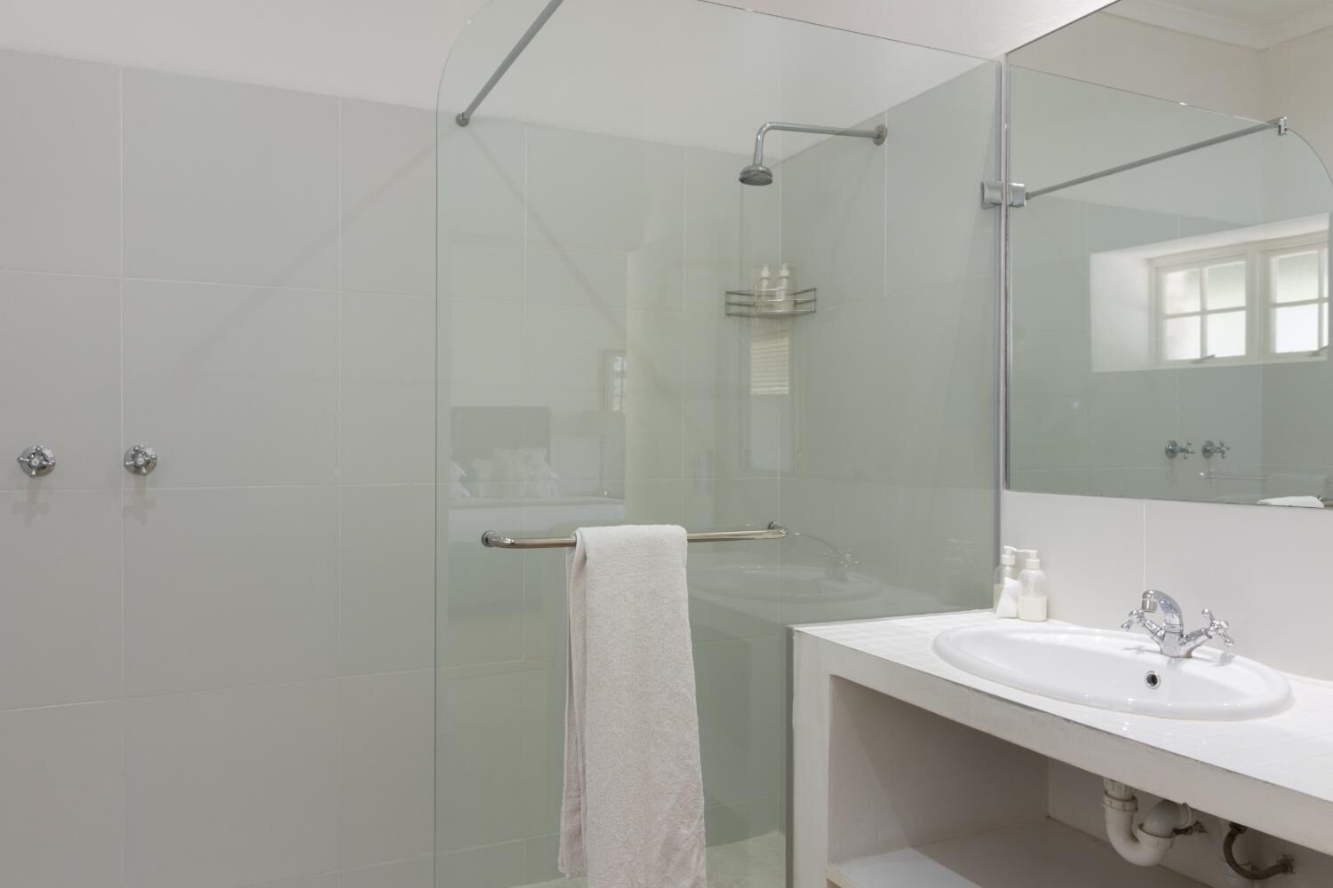 A modern bathroom with a glass-enclosed shower, a white sink, and a large mirror.