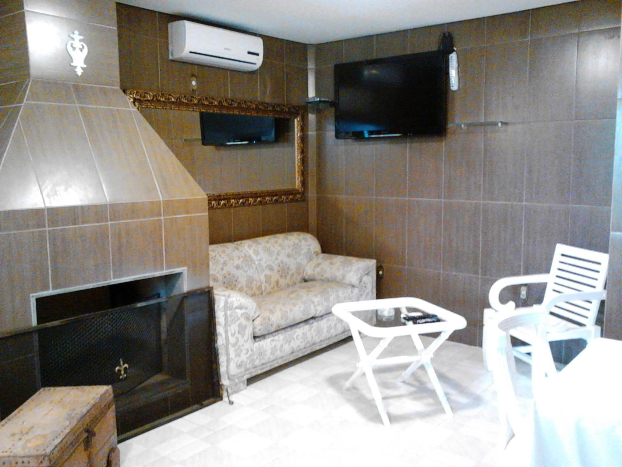 A room with a fireplace, a sofa, a TV mounted on the wall, and a small table with chairs.