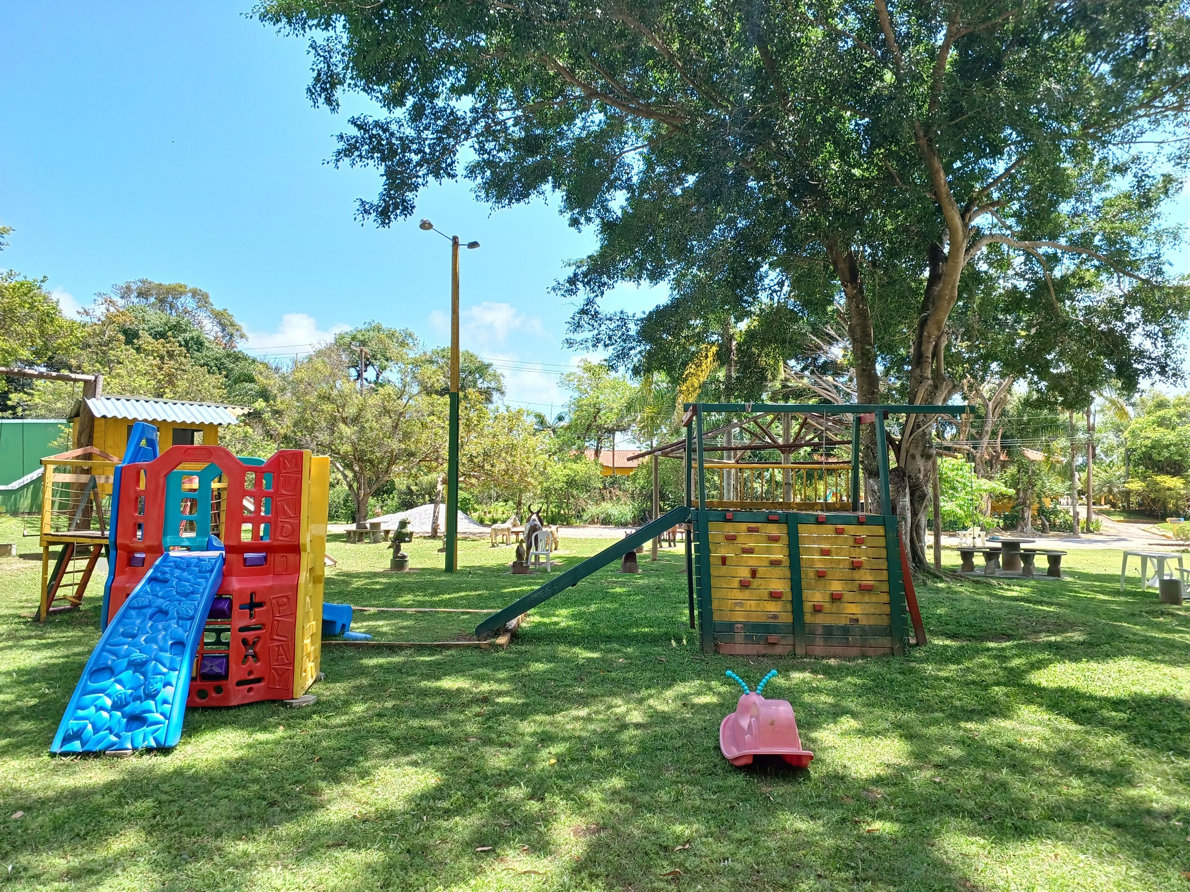 A playground with slides, climbing structures, and a small pink toy car.