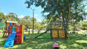 A playground with slides, climbing structures, and a small pink toy car.