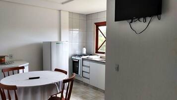 Una cocina con estufa, horno y ventana. Hay una mesa de comedor con sillas.