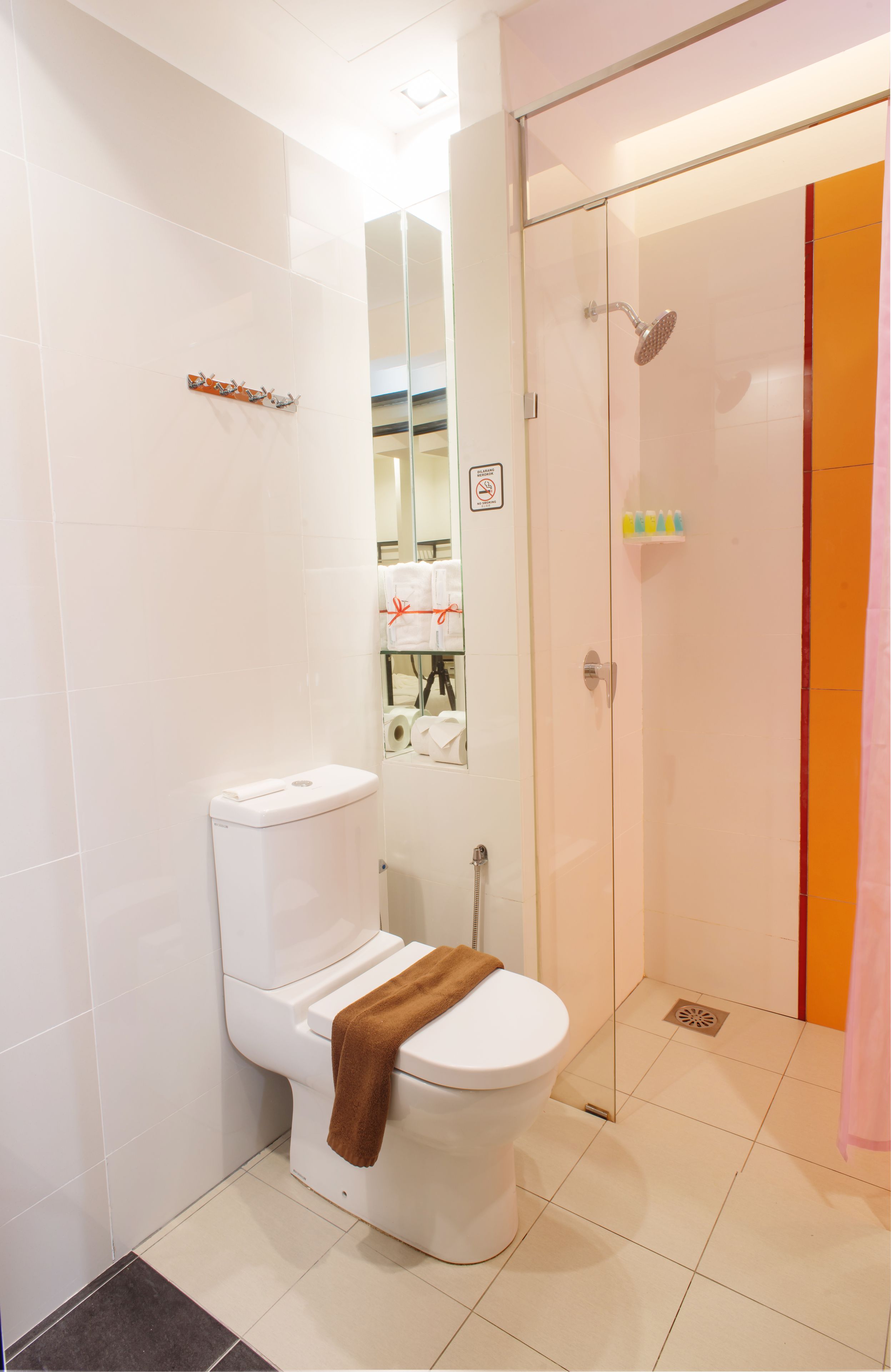 A modern bathroom with a toilet, a glass-enclosed shower, and a mirror.