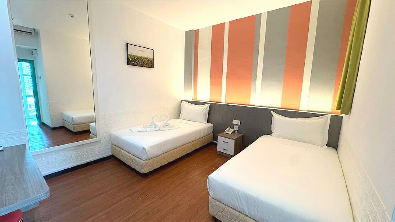 A hotel room with two beds, a bedside table, a nightstand, and a mirror.