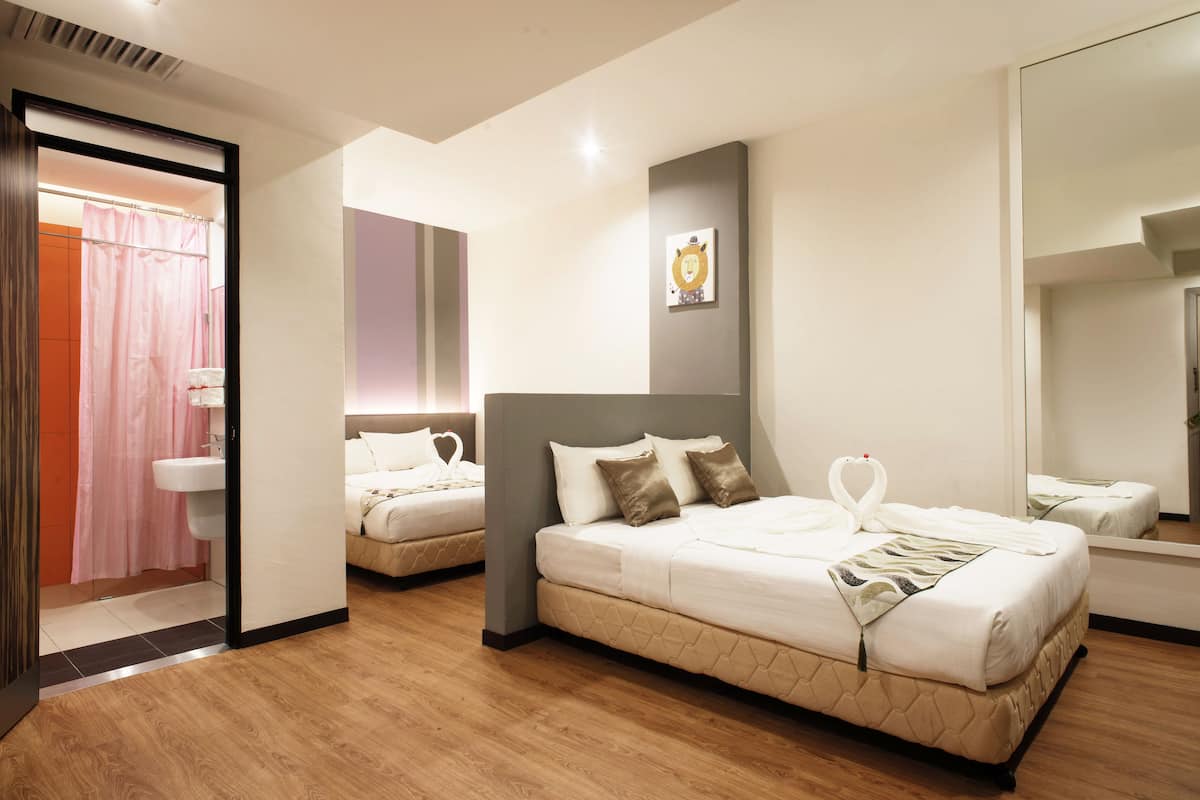 Habitación de hotel con dos camas, un espejo grande y una zona de ducha.
