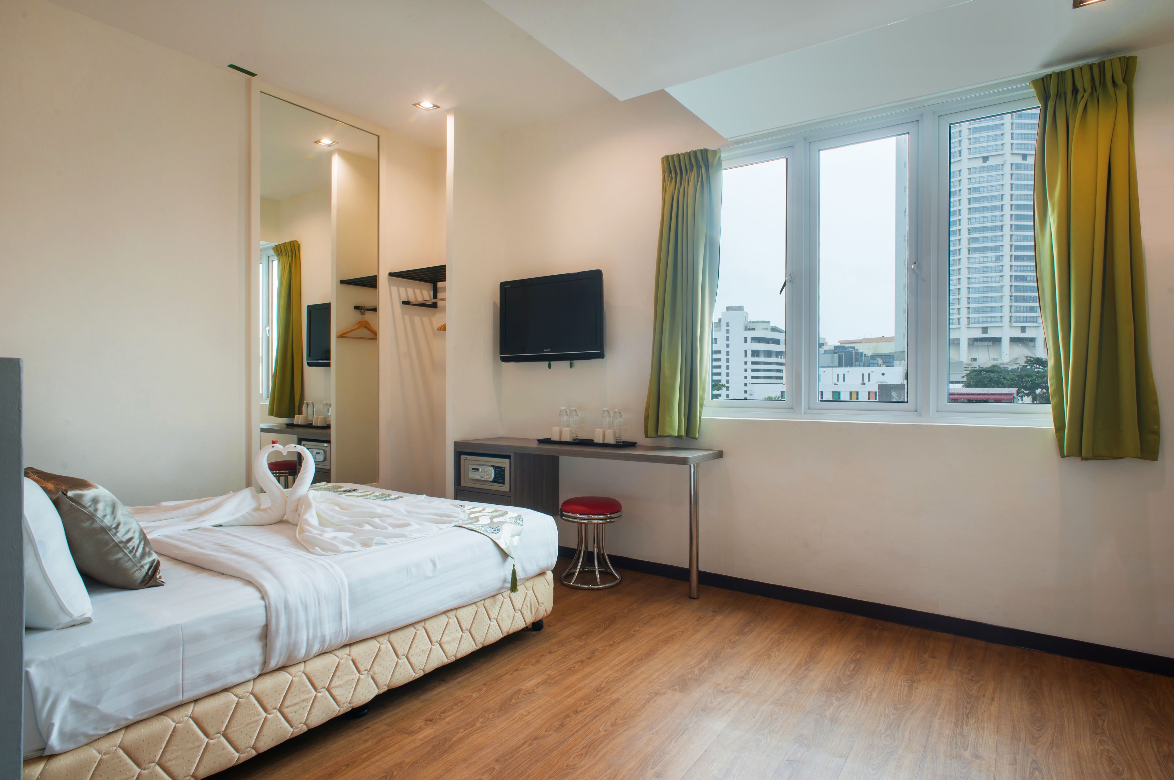 A hotel room with a bed, a desk, a TV, and a window with curtains.